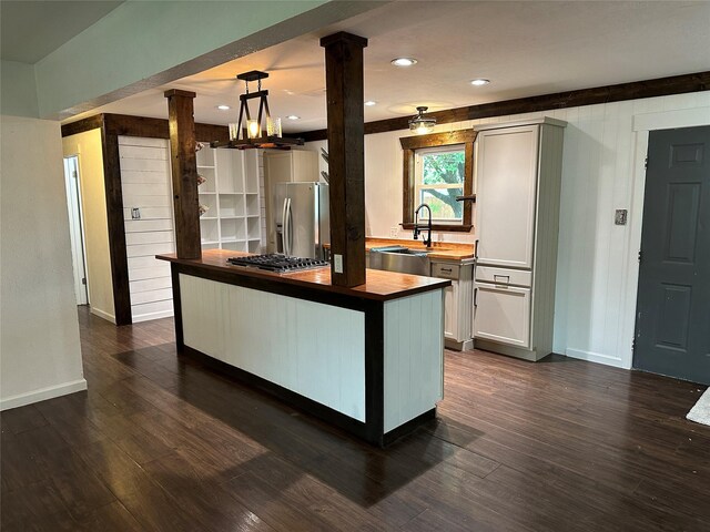 kitchen featuring decorative columns, a sink, baseboards, butcher block counters, and stainless steel appliances