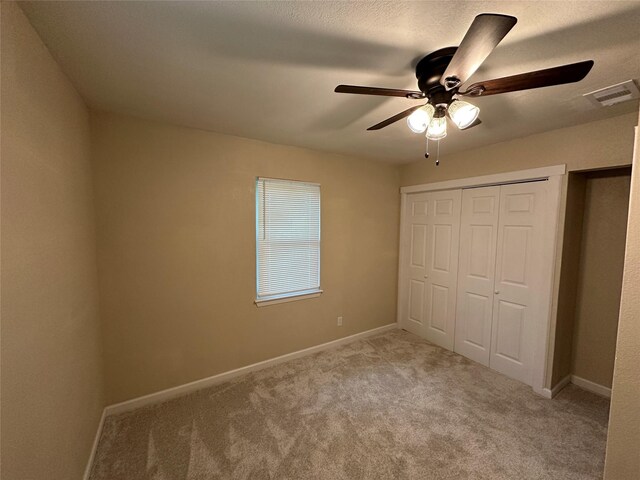 unfurnished bedroom with visible vents, a closet, baseboards, a ceiling fan, and carpet