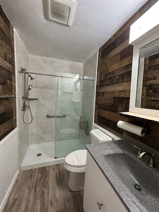 bathroom featuring a shower stall, toilet, wood finished floors, and visible vents