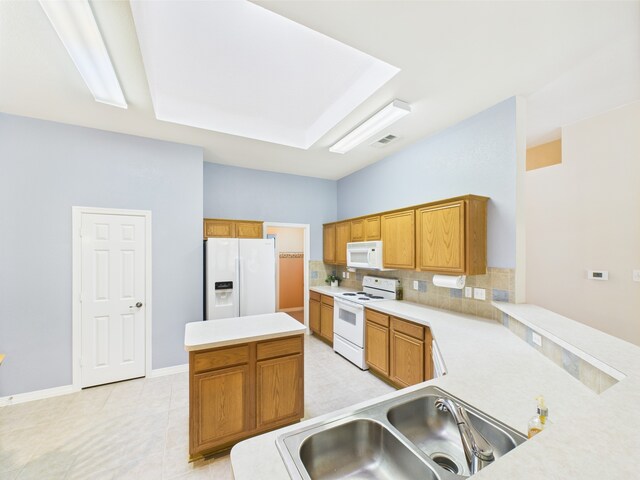 kitchen featuring white appliances, a center island, light countertops, a sink, and backsplash