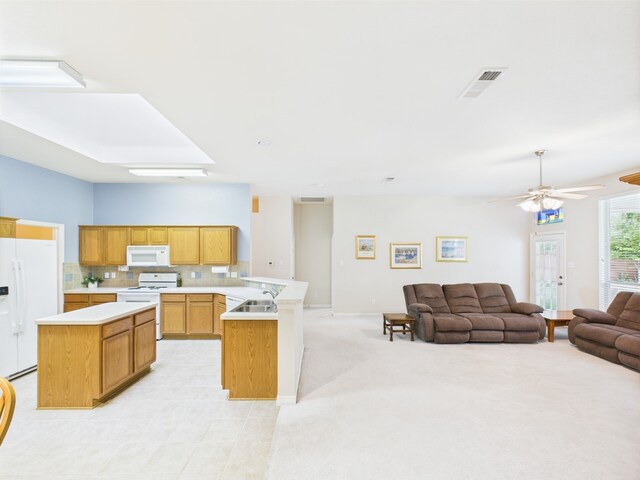 kitchen featuring visible vents, a peninsula, white appliances, open floor plan, and light countertops