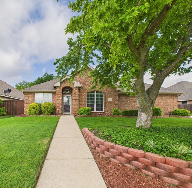 single story home featuring fence, a front yard, and brick siding
