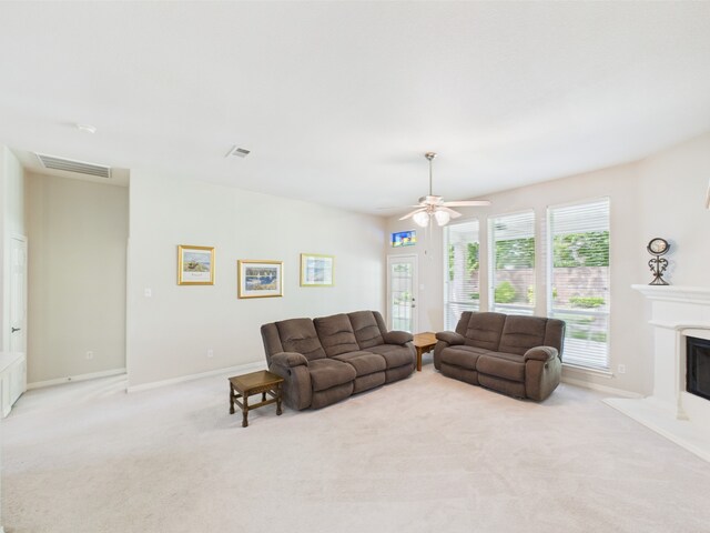 living area with a ceiling fan, visible vents, baseboards, a glass covered fireplace, and carpet