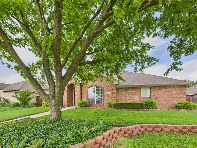 view of front of home with brick siding, a shingled roof, and a front yard