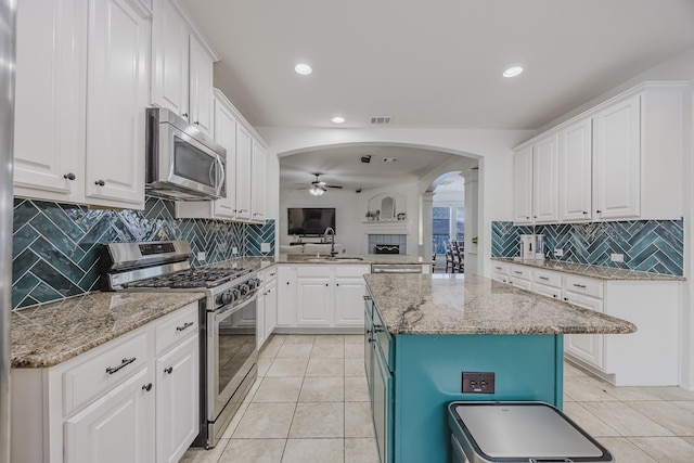 3949 Sunnygate Dr, Fort Worth, TX 76262 - kitchen with appliances with stainless steel finishes, ceiling fan, arched walkways, a sink, and white cabinetry