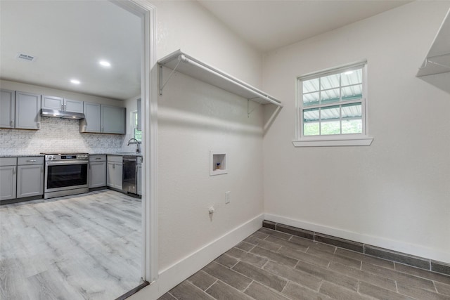 laundry room with washer hookup, a sink, baseboards, wood finished floors, and visible vents