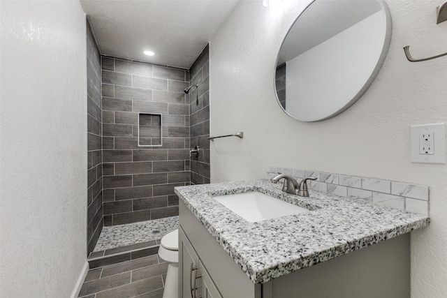 full bathroom with toilet, recessed lighting, a tile shower, and vanity