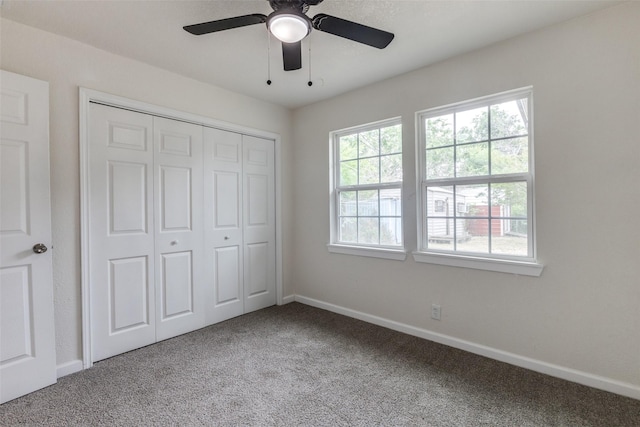 unfurnished bedroom with a closet, carpet flooring, baseboards, and a ceiling fan