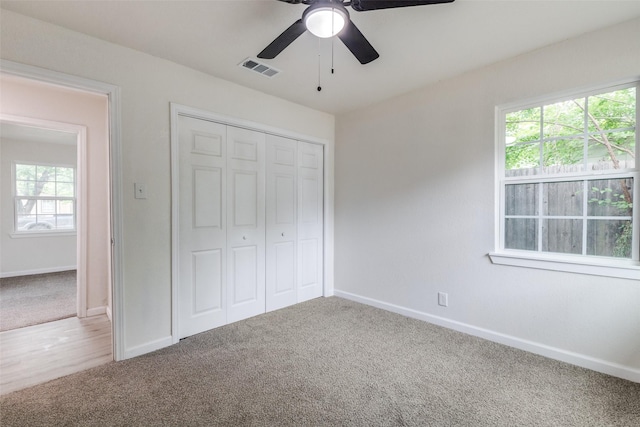 unfurnished bedroom featuring carpet floors, visible vents, multiple windows, and a closet