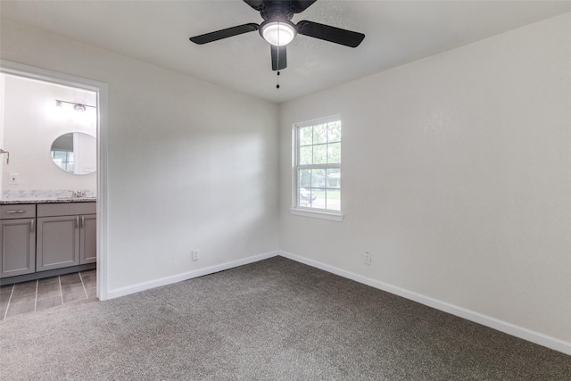carpeted empty room with baseboards, a sink, and ceiling fan