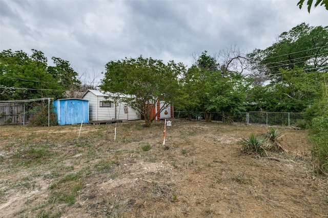 view of yard featuring fence, an outbuilding, and a shed
