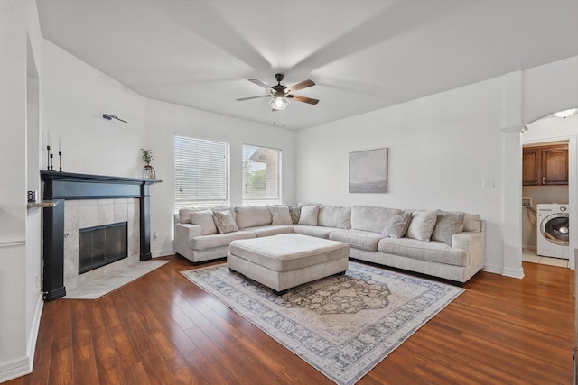 4610 Bluebird Ln, Mansfield, TX 76063 - living room with washer / dryer, ceiling fan, dark wood-style flooring, a tiled fireplace, and baseboards