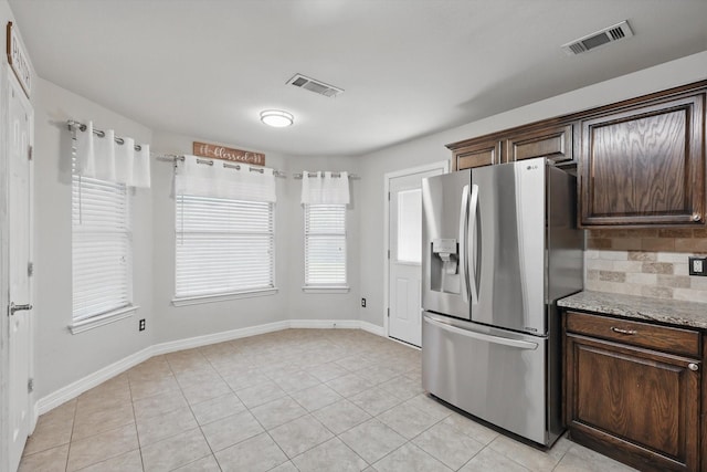 4610 Bluebird Ln, Mansfield, TX 76063 - kitchen featuring stainless steel refrigerator with ice dispenser, dark brown cabinets, light tile patterned flooring, baseboards, and light stone counters