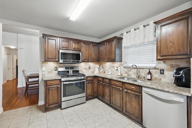 4610 Bluebird Ln, Mansfield, TX 76063 - kitchen featuring appliances with stainless steel finishes, a sink, decorative backsplash, and light stone countertops