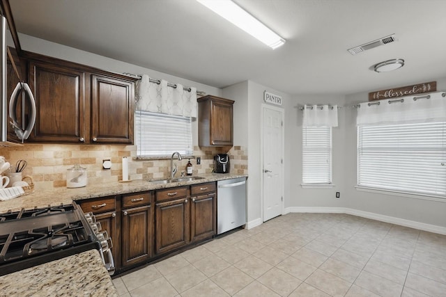 4610 Bluebird Ln, Mansfield, TX 76063 - kitchen featuring a sink, stainless steel appliances, tasteful backsplash, dark brown cabinets, and baseboards
