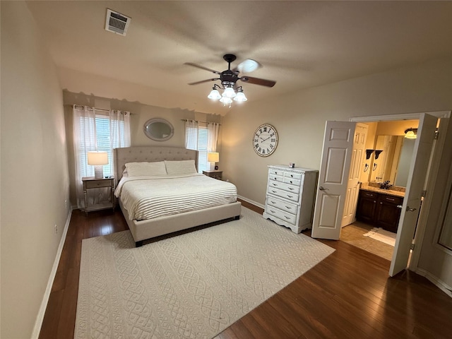 bedroom featuring visible vents, baseboards, ceiling fan, dark wood-style floors, and connected bathroom