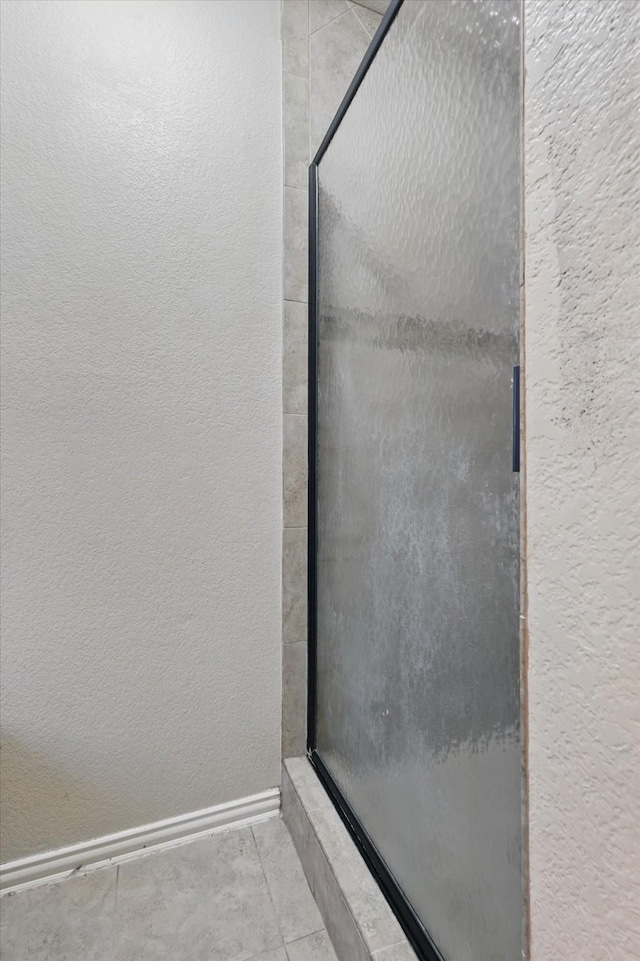 4610 Bluebird Ln, Mansfield, TX 76063 - full bath featuring a textured wall, a shower stall, tile patterned floors, and baseboards