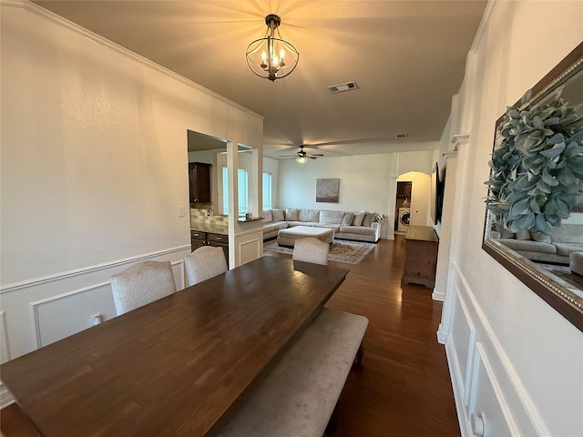 dining area featuring visible vents, arched walkways, dark wood-style flooring, and ceiling fan with notable chandelier