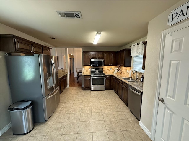 kitchen with backsplash, visible vents, appliances with stainless steel finishes, dark brown cabinets, and a sink