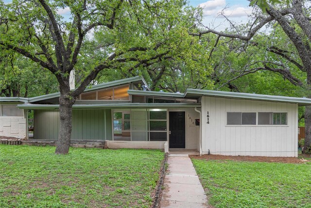 view of front of property with a sunroom and a front yard