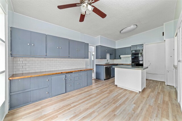 kitchen featuring decorative backsplash, dobule oven black, a textured ceiling, a sink, and light wood-style flooring