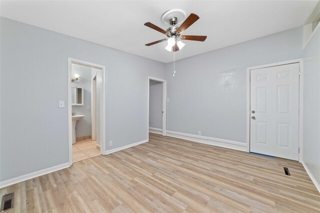 interior space featuring ceiling fan, visible vents, baseboards, and light wood finished floors