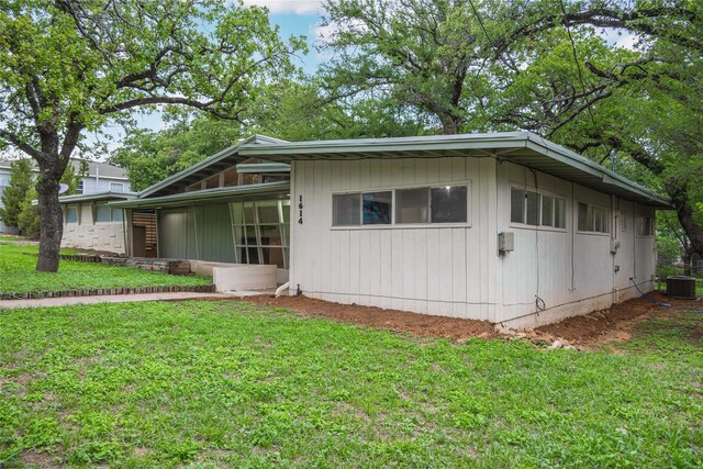 view of side of home with a lawn, a sunroom, and cooling unit