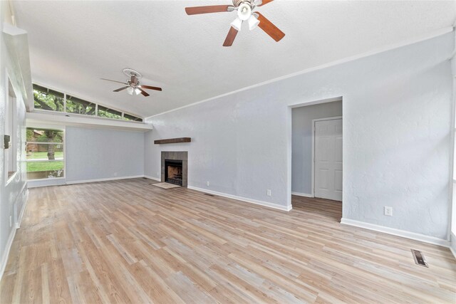 unfurnished living room featuring lofted ceiling, a fireplace, light wood-style floors, baseboards, and ceiling fan