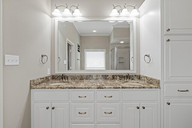 bathroom with a sink, crown molding, a stall shower, and double vanity