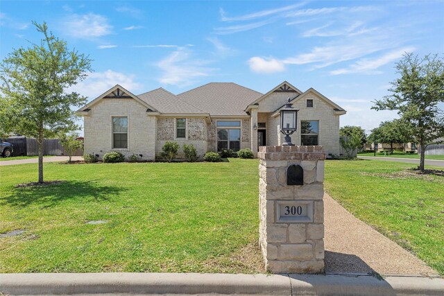 view of front of house featuring brick siding, fence, and a front lawn
