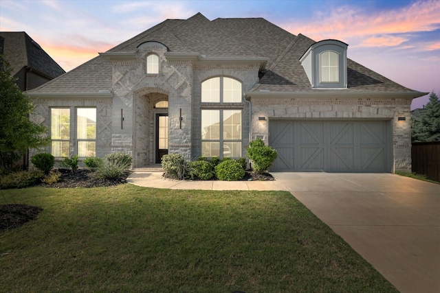 3320 Alexandra Ln, Celina, TX 75009 - french country inspired facade with concrete driveway, a garage, roof with shingles, a lawn, and brick siding