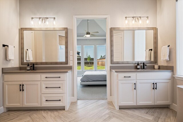 carpeted bedroom featuring baseboards, ensuite bathroom, a ceiling fan, and a raised ceiling