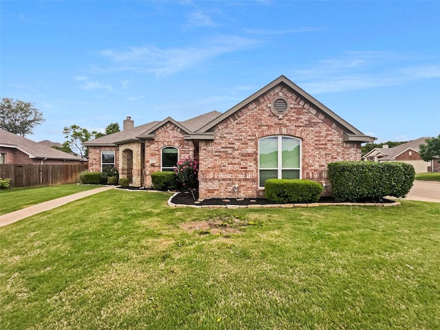 view of front of property with fence, roof with shingles, brick siding, a front yard, and a chimney