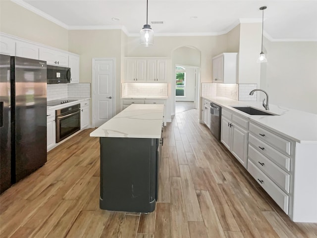 kitchen with white cabinetry, decorative backsplash, a sink, and black appliances