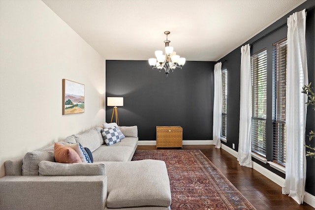 living area with baseboards, an inviting chandelier, and wood finished floors