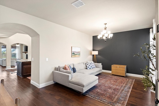 living room with baseboards, arched walkways, dark wood-style flooring, and visible vents