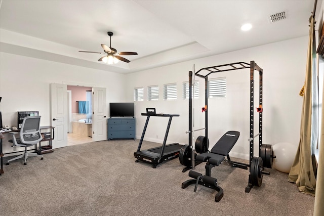 workout room with visible vents, carpet flooring, baseboards, a raised ceiling, and a ceiling fan
