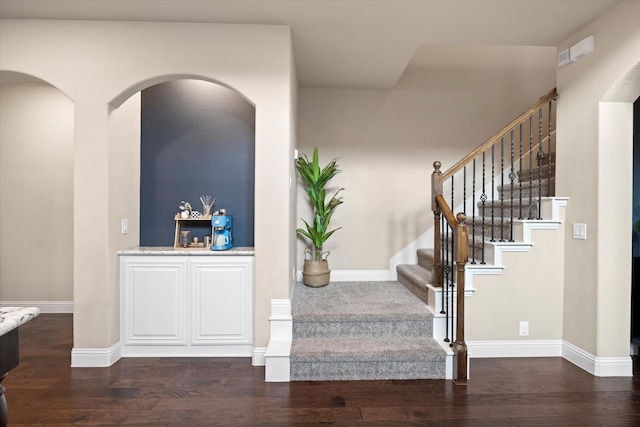 interior space featuring baseboards, arched walkways, and wood finished floors
