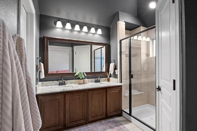 full bath with double vanity, tile patterned flooring, a stall shower, and a sink