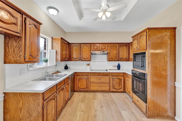 kitchen featuring under cabinet range hood, brown cabinetry, a sink, and black appliances