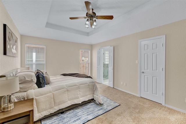 bedroom with carpet floors, multiple windows, ensuite bathroom, and a tray ceiling