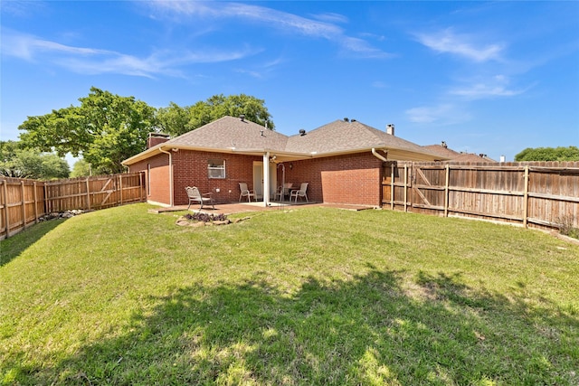 back of house featuring a fenced backyard, a chimney, brick siding, a patio area, and a lawn