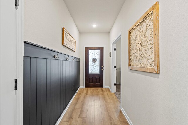 doorway featuring baseboards and light wood finished floors