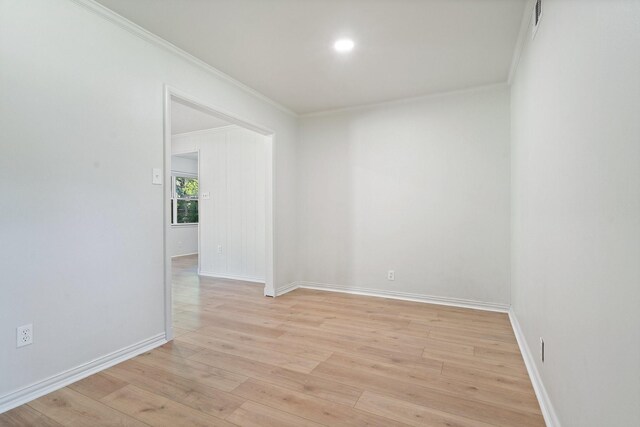 spare room with crown molding, baseboards, and light wood-style flooring