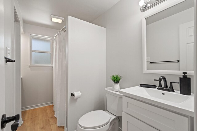 bathroom featuring wood finished floors, curtained shower, vanity, baseboards, and toilet