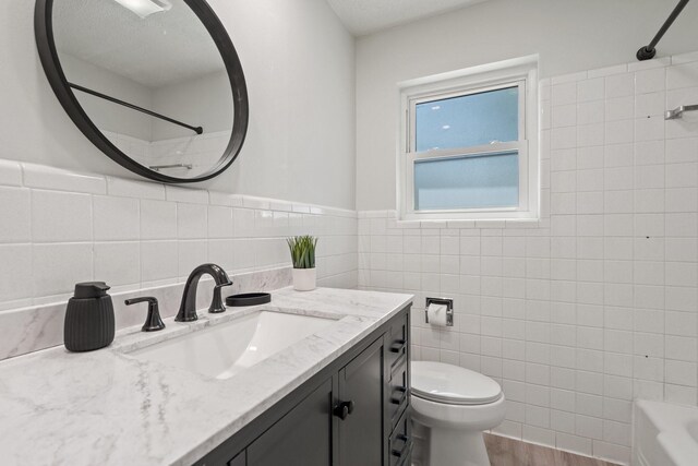 full bath featuring shower / bathing tub combination, tile walls, wood finished floors, vanity, and toilet