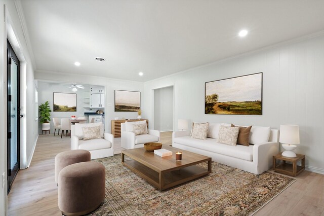 living room with light wood-type flooring, ornamental molding, visible vents, and recessed lighting