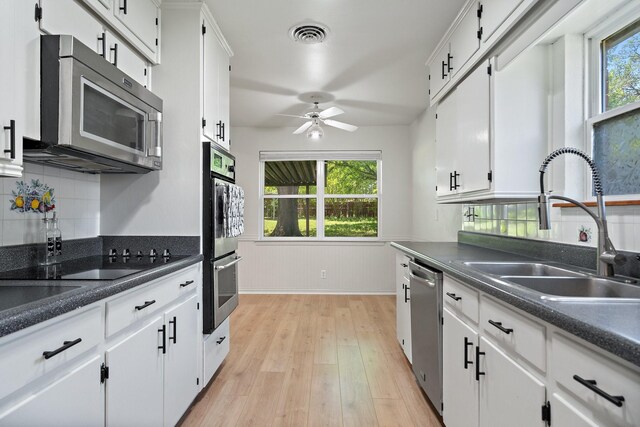 kitchen featuring visible vents, a sink, white cabinets, light wood-style floors, and stainless steel appliances