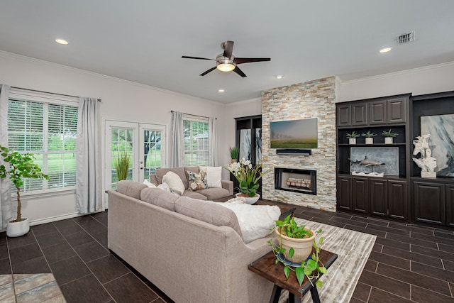 living area with ceiling fan, a stone fireplace, recessed lighting, visible vents, and ornamental molding