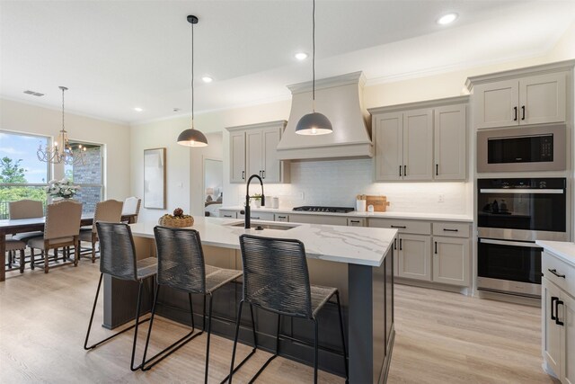 kitchen featuring a sink, double oven, built in microwave, premium range hood, and gray cabinetry